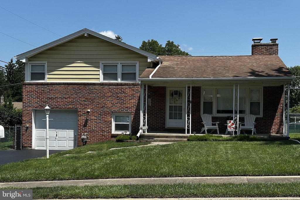 2423 Wharton Rd, York, PA 17402 - view of front of house featuring brick siding, a garage, driveway, and a chimney
