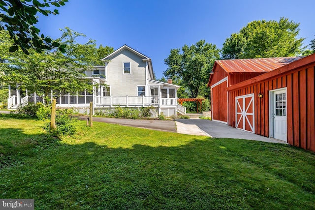 1012 Grant St, Herndon, VA 20170 - rear view of house with a lawn, an outdoor structure, a sunroom, and board and batten siding