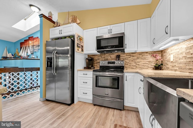 47 Sheridan Rd, Arnold, MD 21012 - kitchen with appliances with stainless steel finishes, a skylight, white cabinetry, backsplash, and lofted ceiling