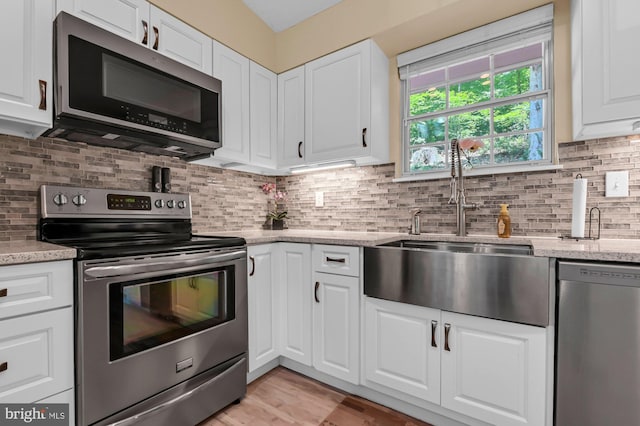 47 Sheridan Rd, Arnold, MD 21012 - kitchen with stainless steel appliances, white cabinetry, light stone counters, and tasteful backsplash