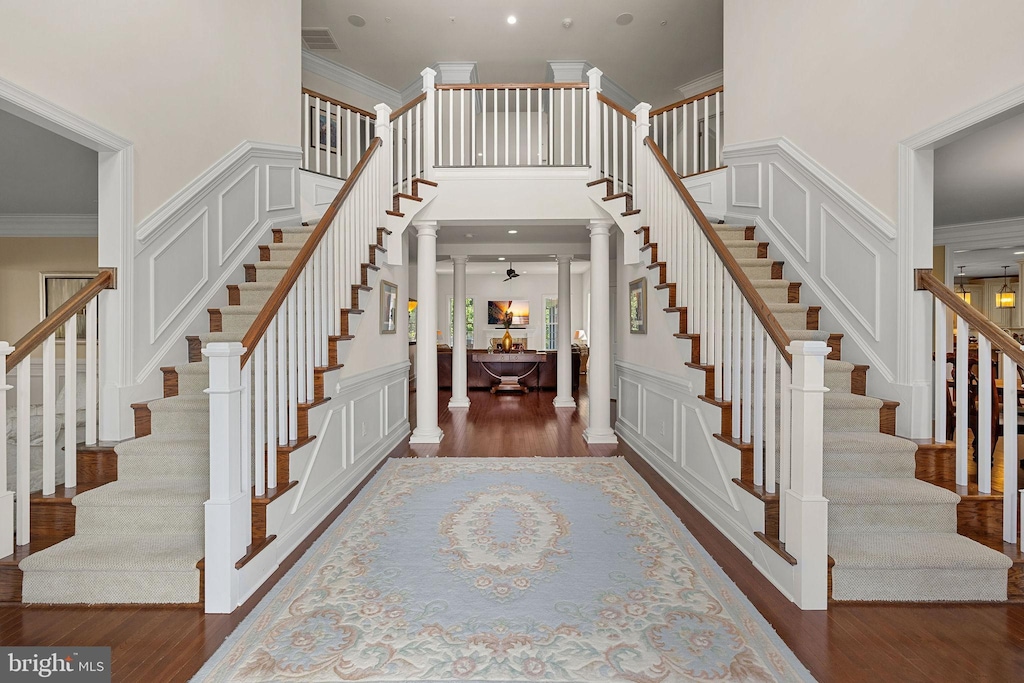 4400 Palomino Xing, Upper Marlboro, MD 20772 - staircase featuring ornamental molding, ornate columns, wood finished floors, a decorative wall, and a towering ceiling