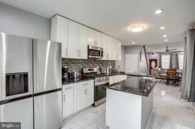 2057 N Franklin St, Philadelphia, PA 19122 - kitchen featuring stainless steel appliances, light marble finish floors, a peninsula, tasteful backsplash, and white cabinetry