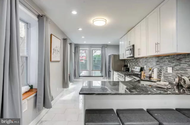 2057 N Franklin St, Philadelphia, PA 19122 - kitchen with stainless steel appliances, dark stone countertops, decorative backsplash, white cabinets, and a peninsula