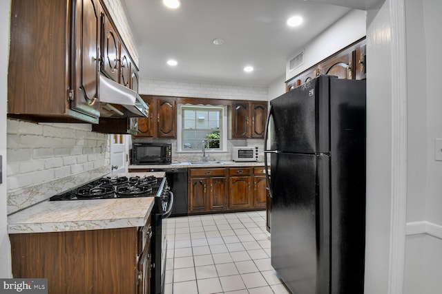 1627 Myrtle St NW, Washington, DC 20012 - kitchen featuring black appliances, under cabinet range hood, light countertops, light tile patterned floors, and tasteful backsplash