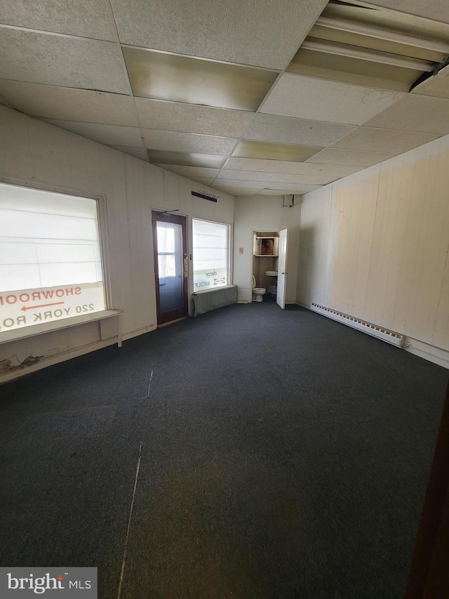 220 York Rd, Jenkintown, PA 19046 - empty room with a baseboard radiator, a paneled ceiling, dark carpet, and wood walls