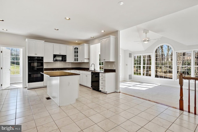 1050 Northfalls Ct, Great Falls, VA 22066 - kitchen with black appliances, a center island, dark countertops, light tile patterned flooring, and healthy amount of natural light