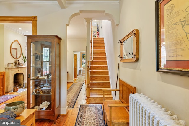 637 Constitution Ave NE, Washington, DC 20002 - hallway with radiator heating unit, light wood-type flooring, crown molding, ornate columns, and arched walkways