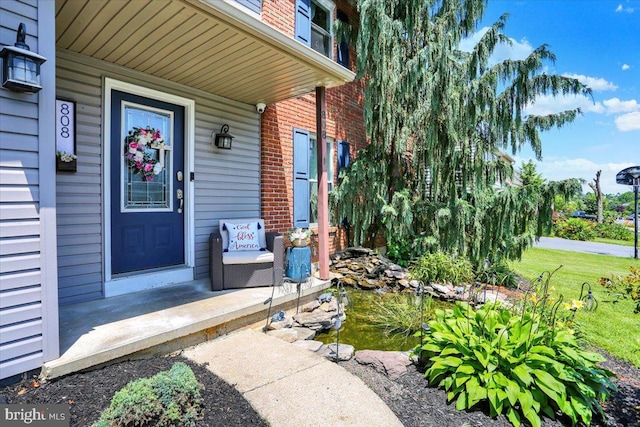 808 Redwood Ave, Reading, PA 19610 - doorway to property with brick siding, a garden pond, covered porch, and a security system