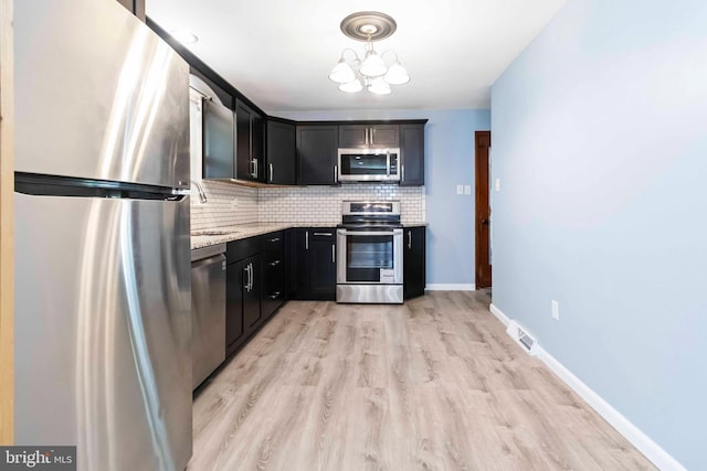 663 Newberry Rd, Middletown, PA 17057 - kitchen with stainless steel appliances, tasteful backsplash, light stone counters, a chandelier, and light wood finished floors