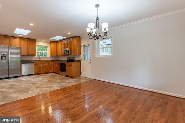 10311 Poe Dr, Manassas, VA 20110 - kitchen with stainless steel appliances, dark countertops, ornamental molding, brown cabinets, and a chandelier
