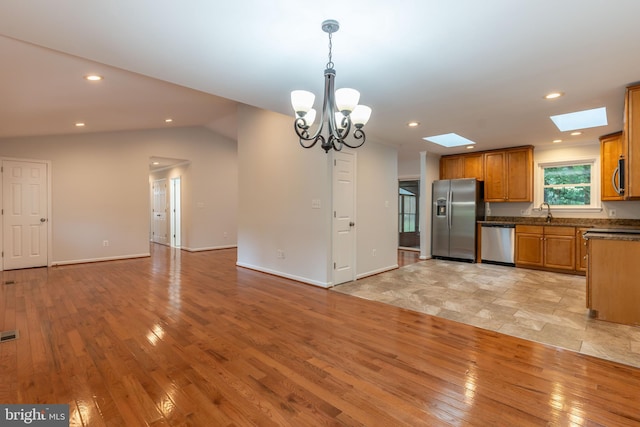 10311 Poe Dr, Manassas, VA 20110 - kitchen with stainless steel appliances, dark countertops, a skylight, brown cabinetry, and light wood-style floors