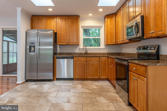 10311 Poe Dr, Manassas, VA 20110 - kitchen with stainless steel appliances, a skylight, brown cabinets, and recessed lighting