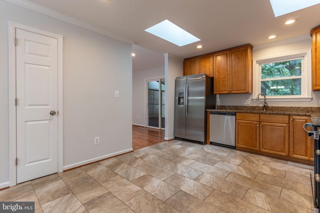 10311 Poe Dr, Manassas, VA 20110 - kitchen with a skylight, appliances with stainless steel finishes, crown molding, brown cabinets, and light stone finish floors