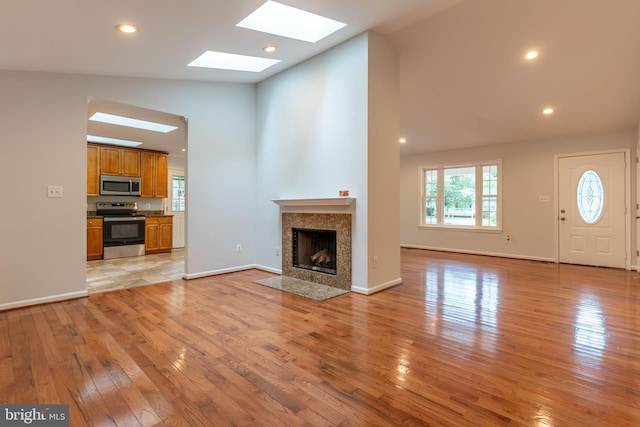 10311 Poe Dr, Manassas, VA 20110 - unfurnished living room featuring a skylight, high vaulted ceiling, light wood-type flooring, a tiled fireplace, and recessed lighting