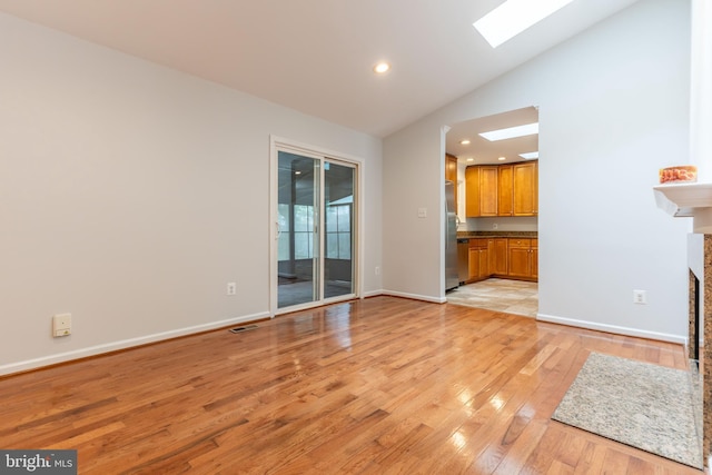 10311 Poe Dr, Manassas, VA 20110 - unfurnished living room featuring a skylight, light wood-style floors, recessed lighting, a fireplace, and high vaulted ceiling