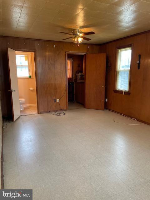 6813 10th Ave, Takoma Park, MD 20912 - spare room with light flooring, wooden walls, and a ceiling fan