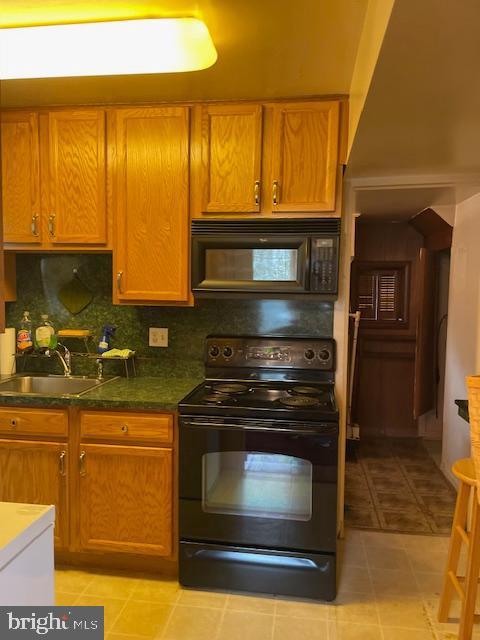 6813 10th Ave, Takoma Park, MD 20912 - kitchen featuring black appliances, backsplash, brown cabinets, light tile patterned flooring, and dark countertops