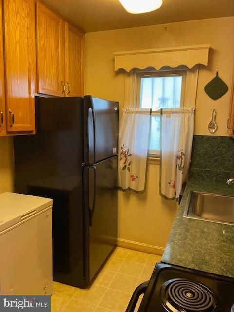 6813 10th Ave, Takoma Park, MD 20912 - kitchen with black appliances, brown cabinets, and light tile patterned floors