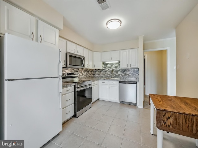 1042 Brinker Dr, Hagerstown, MD 21740 - kitchen with appliances with stainless steel finishes, decorative backsplash, white cabinets, light tile patterned floors, and crown molding