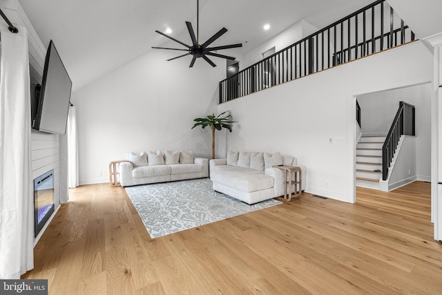 9 W Shore Ct, Landenberg, PA 19350 - living area with stairway, high vaulted ceiling, ceiling fan, light wood finished floors, and a glass covered fireplace