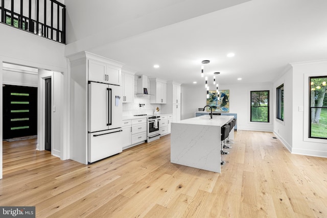 9 W Shore Ct, Landenberg, PA 19350 - kitchen with high end white fridge, wall chimney exhaust hood, white cabinets, light wood-style flooring, and an island with sink
