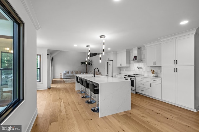 9 W Shore Ct, Landenberg, PA 19350 - kitchen with stainless steel stove, wall chimney exhaust hood, freestanding refrigerator, crown molding, and light wood-style flooring
