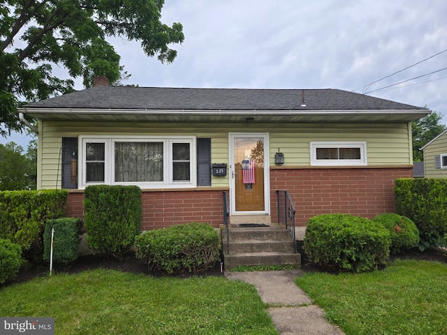 235 S Main St, Quakertown, PA 18951 - bungalow-style house with brick siding, a chimney, a front yard, and roof with shingles