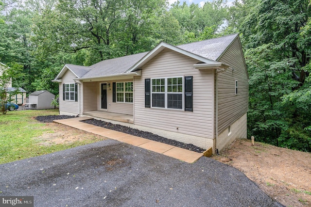 114 Dragoon Dr, Montross, VA 22520 - view of front of home with a porch, a storage unit, roof with shingles, and view of wooded area