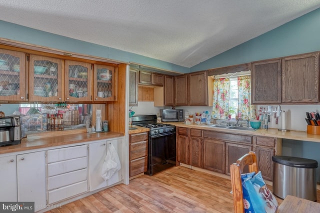 25036 Becks Ln, Georgetown, DE 19947 - kitchen with black gas stove, stainless steel microwave, vaulted ceiling, light wood-type flooring, and light countertops