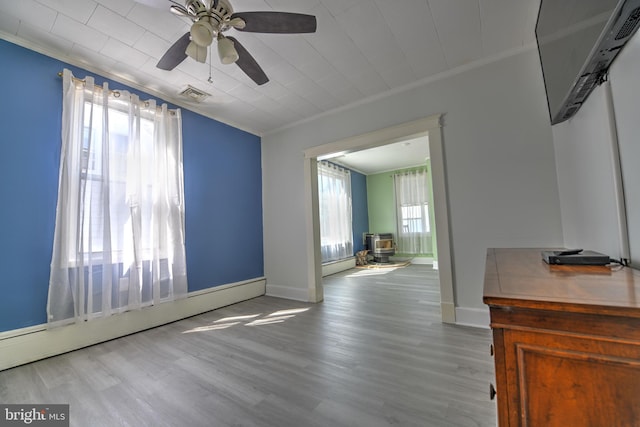 5417 Wasena Ave, Baltimore, MD 21225 - unfurnished living room featuring ornamental molding, a wood stove, a baseboard heating unit, a ceiling fan, and wood finished floors