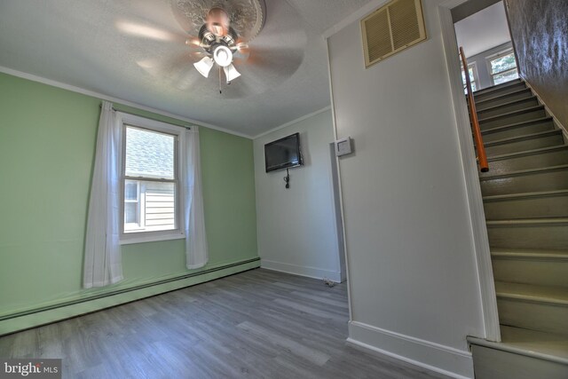 5417 Wasena Ave, Baltimore, MD 21225 - empty room with a baseboard heating unit, a ceiling fan, stairway, wood finished floors, and plenty of natural light