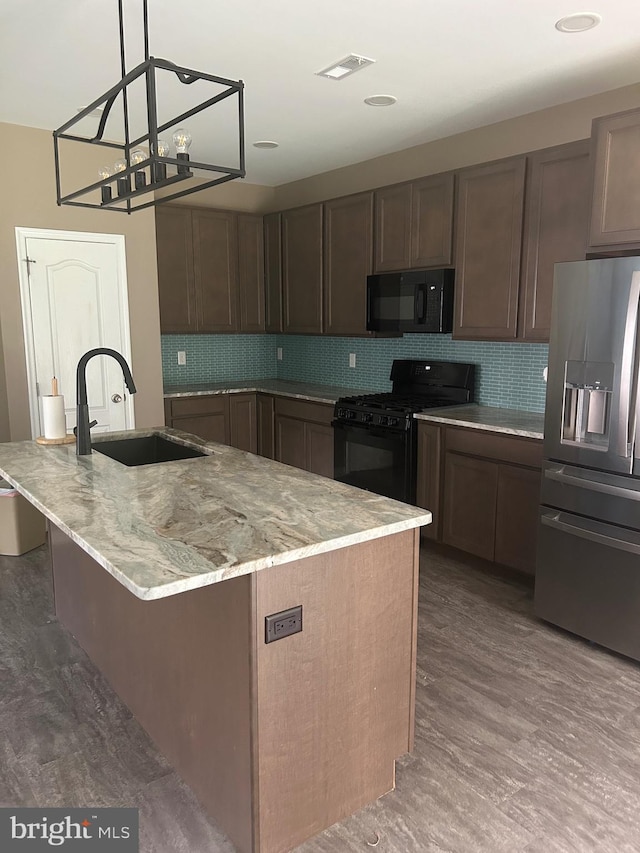 655 Morris Ave, Newfield, NJ 08344 - kitchen with black appliances, decorative backsplash, light stone countertops, an island with sink, and pendant lighting