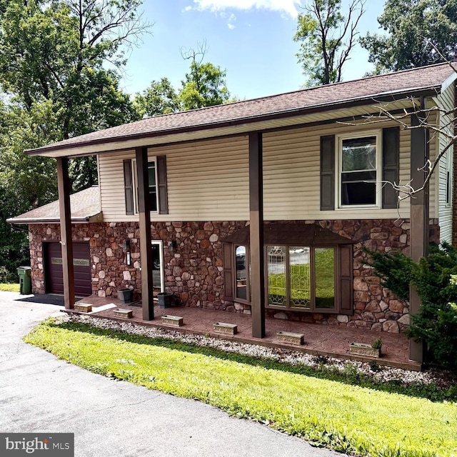 24 Wagner Cir, Hummelstown, PA 17036 - view of front of property featuring stone siding, an attached garage, roof with shingles, asphalt driveway, and a front lawn