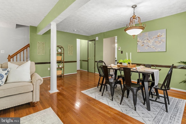 2508 Smoketree Ln, Crofton, MD 21114 - dining room featuring decorative columns, a textured ceiling, wood finished floors, and stairway
