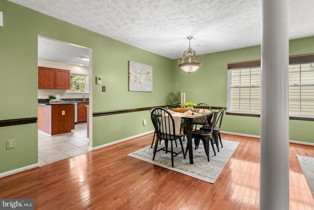 2508 Smoketree Ln, Crofton, MD 21114 - dining room featuring a textured ceiling, light wood-style floors, and decorative columns