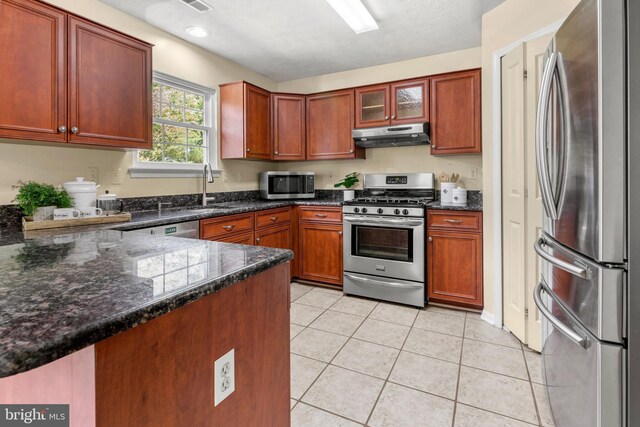 2508 Smoketree Ln, Crofton, MD 21114 - kitchen with stainless steel appliances, under cabinet range hood, light tile patterned floors, dark stone counters, and a peninsula