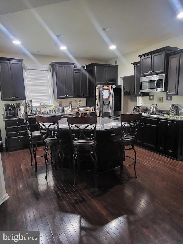 2511 Sir Michael Pl, Lanham, MD 20706 - kitchen with stainless steel appliances, dark wood-style flooring, a kitchen island, a breakfast bar area, and light stone counters