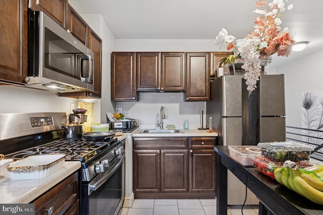 2467 79th Ave, Philadelphia, PA 19150 - kitchen with appliances with stainless steel finishes, light countertops, light tile patterned floors, and dark brown cabinetry