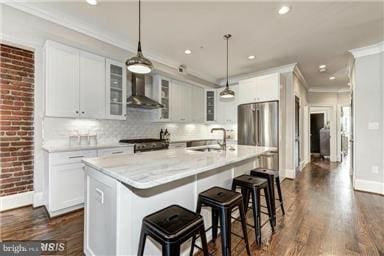 3624 10th St NW Unit 4, Washington, DC 20010 - kitchen featuring wall chimney range hood, dark wood finished floors, a kitchen island with sink, crown molding, and light countertops