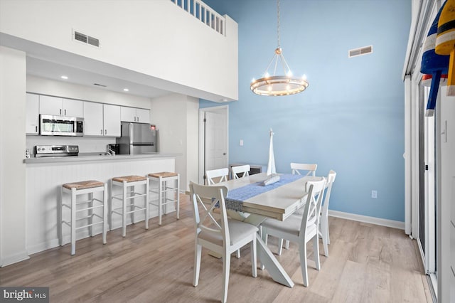 39334 Tall Pines Ct Unit 15001, Bethany Beach, DE 19930 - dining area featuring a towering ceiling, light wood-type flooring, and a chandelier