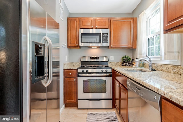 6910 Quander Rd, Alexandria, VA 22307 - kitchen with stainless steel appliances, light stone counters, light tile patterned flooring, and brown cabinetry