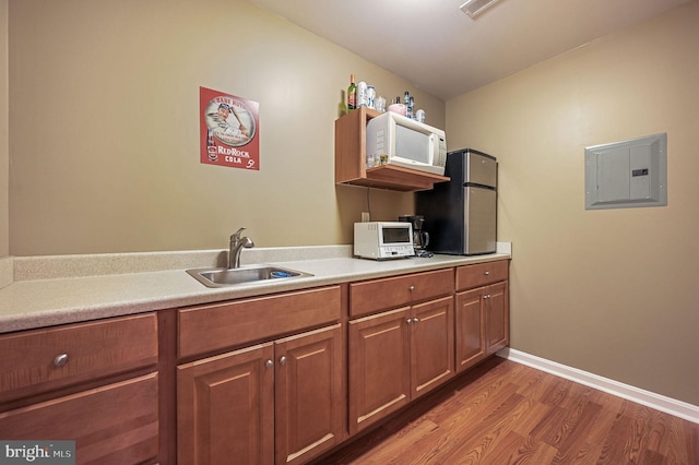 45 Harcrest Ct, Dover, DE 19901 - kitchen with electric panel, wood finished floors, light countertops, brown cabinetry, and white microwave