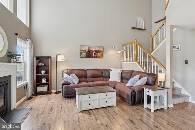 2405 Carriage Ln, Royersford, PA 19468 - living area featuring stairs, light wood-type flooring, a glass covered fireplace, and a towering ceiling