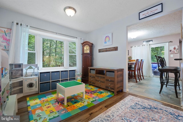 11590 Mohican Rd, Woodbridge, VA 22192 - rec room with washer / clothes dryer, healthy amount of natural light, a textured ceiling, and wood finished floors