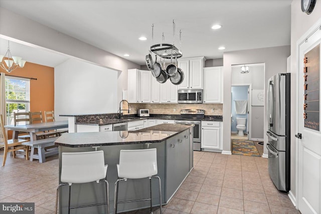 7 Kettlebrook Ct, Stafford, VA 22556 - kitchen featuring appliances with stainless steel finishes, backsplash, a peninsula, white cabinetry, and light tile patterned floors
