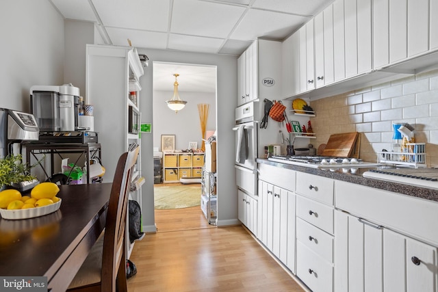 801 Yale Ave Unit 1016, Swarthmore, PA 19081 - kitchen featuring light wood finished floors, a paneled ceiling, decorative backsplash, white cabinetry, and white oven