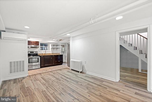 1425 Webster St NW, Washington, DC 20011 - kitchen with stainless steel range with electric stovetop, a wall mounted AC, radiator, under cabinet range hood, and light wood-type flooring