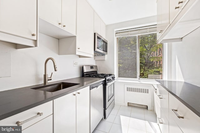 4100 W St NW Unit 306, Washington, DC 20007 - kitchen with appliances with stainless steel finishes, radiator, dark countertops, and white cabinets