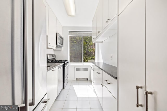 4100 W St NW Unit 306, Washington, DC 20007 - kitchen with appliances with stainless steel finishes, white cabinets, radiator heating unit, and light tile patterned floors