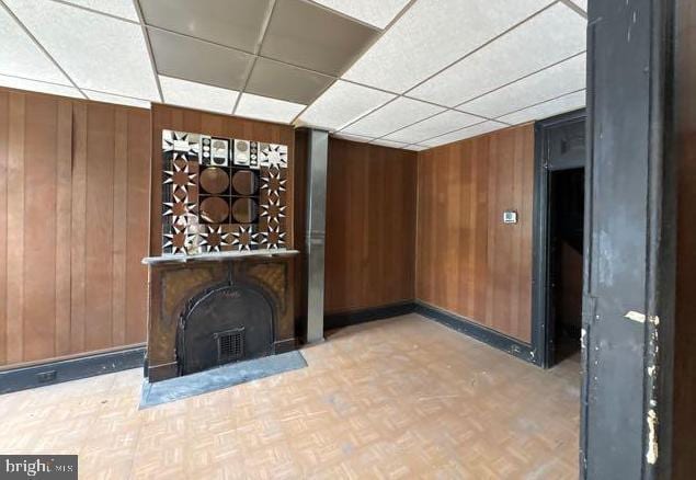 324 Fulton Ave, Baltimore, MD 21223 - unfurnished living room featuring a paneled ceiling and wood walls